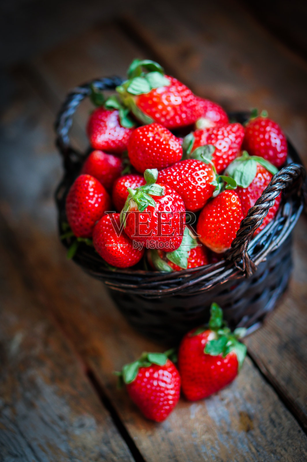 一篮新鲜的草莓放在木头背景上照片摄影图片