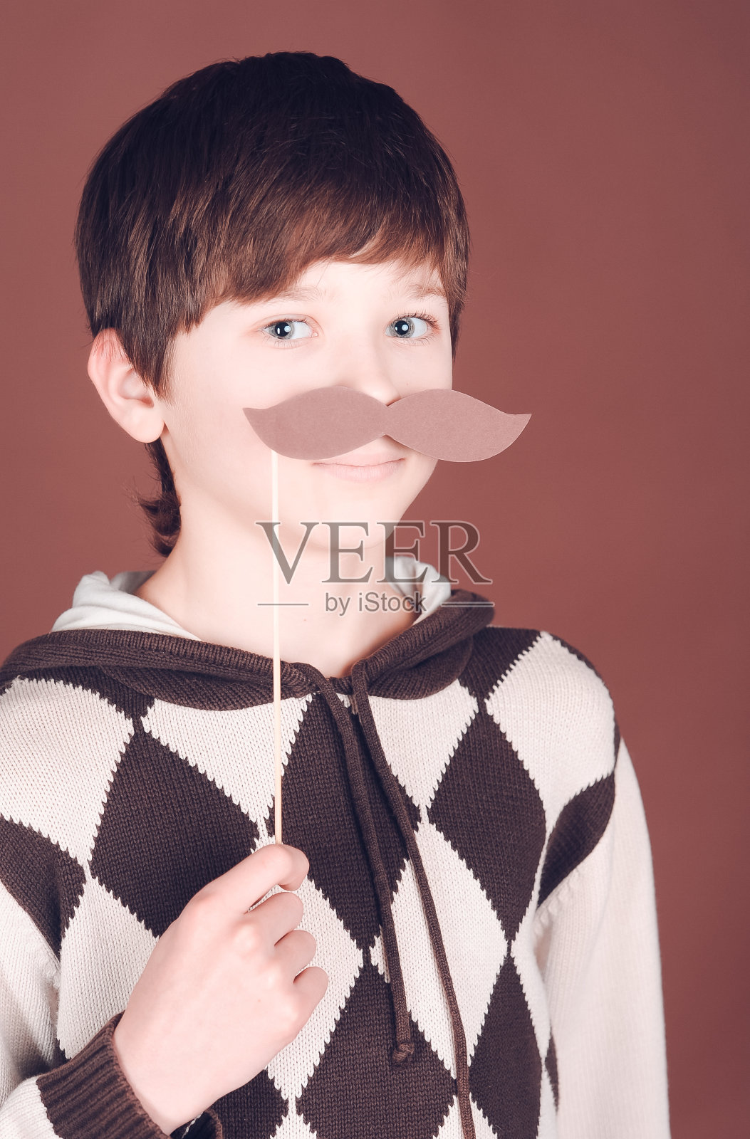 可爱的男孩拿着装饰的小胡子照片摄影图片