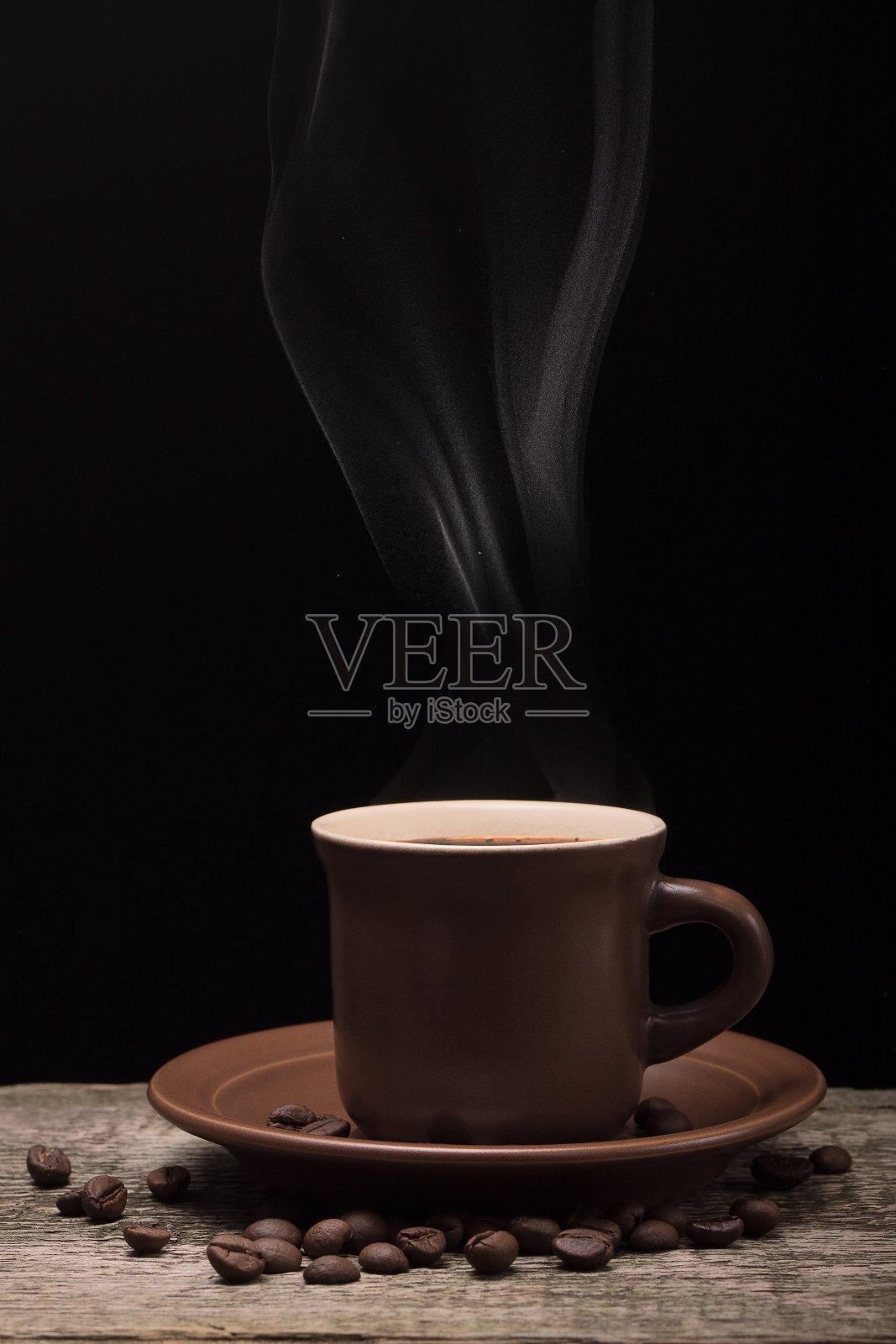 咖啡与轻蒸汽和豆在黑色背景照片摄影图片