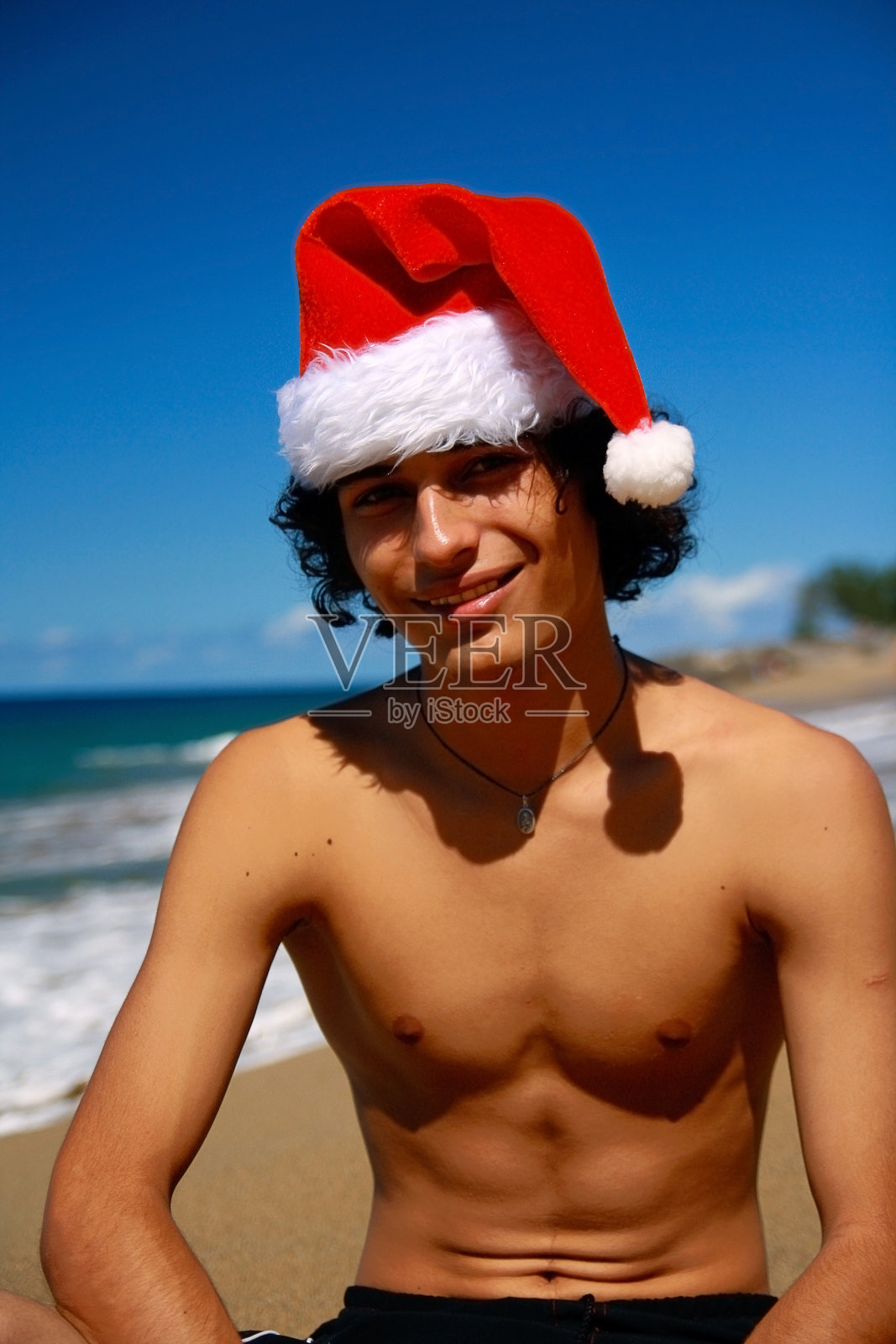 海滩上戴着圣诞老人帽的男人照片摄影图片