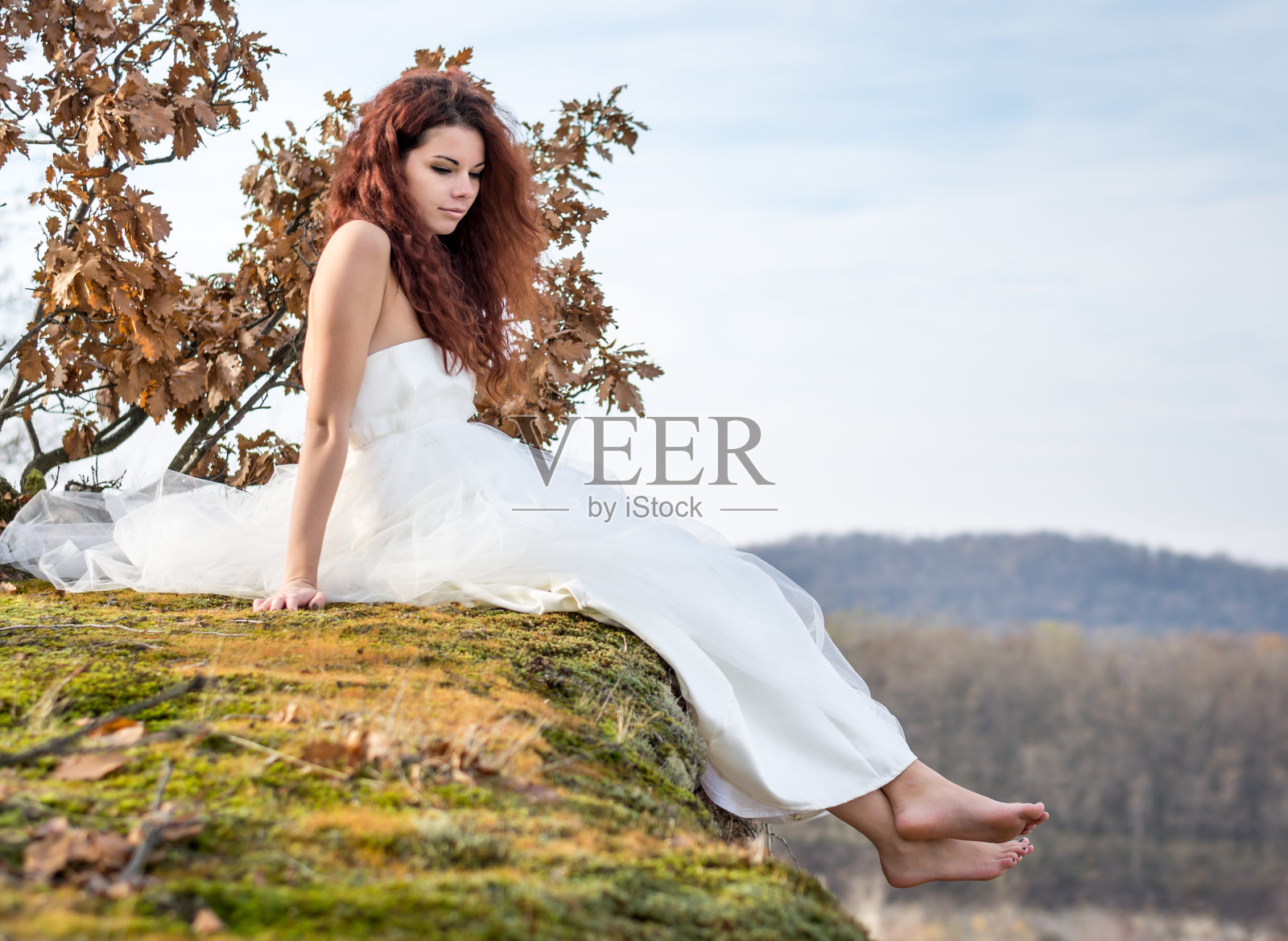 坐在悬崖边上的年轻女子照片摄影图片