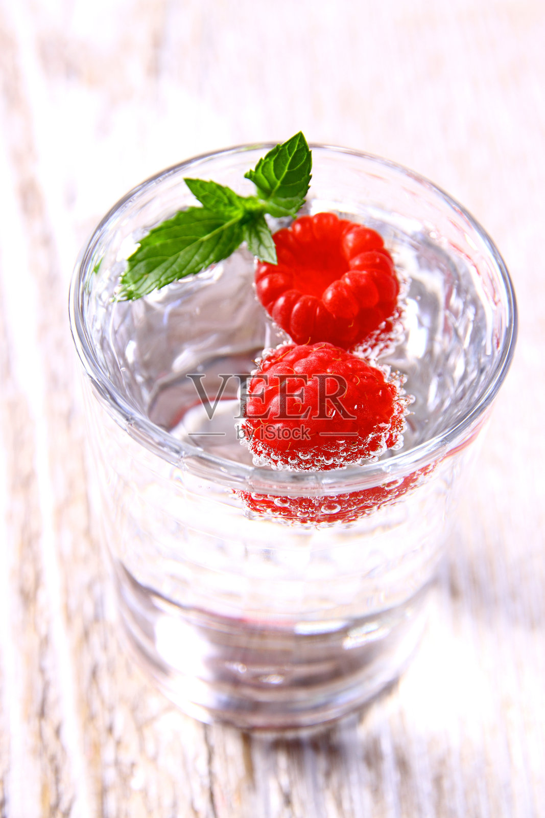 玻璃杯里的两个覆盆子加水和薄荷叶照片摄影图片