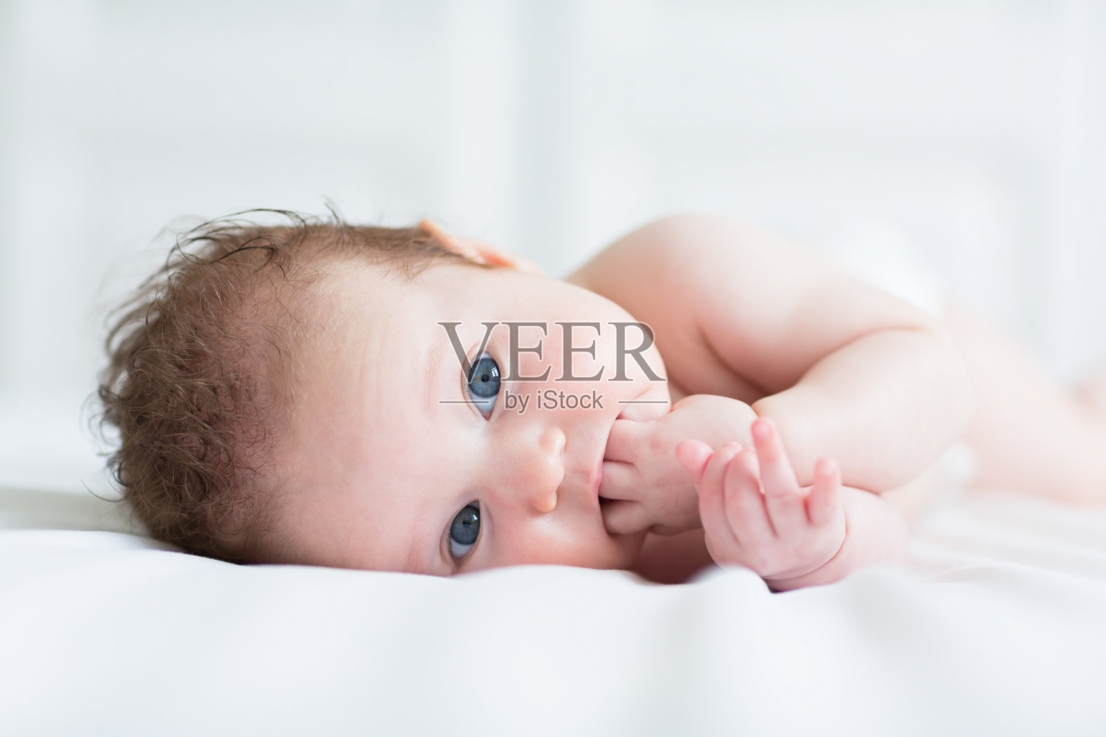 可爱的蓝眼睛婴儿吮吸着手指照片摄影图片