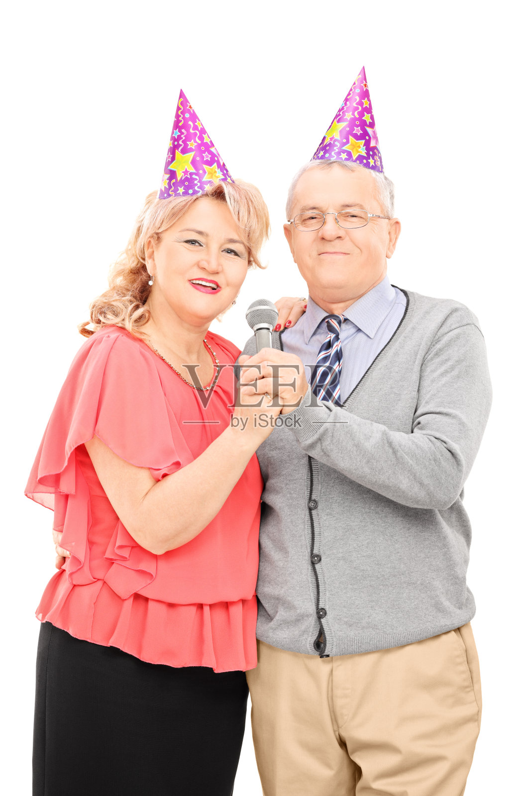 戴派对帽的成熟情侣对着麦克风唱歌照片摄影图片