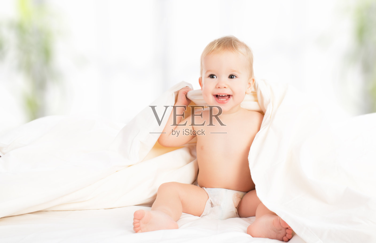 快乐的婴儿在毯子下笑照片摄影图片