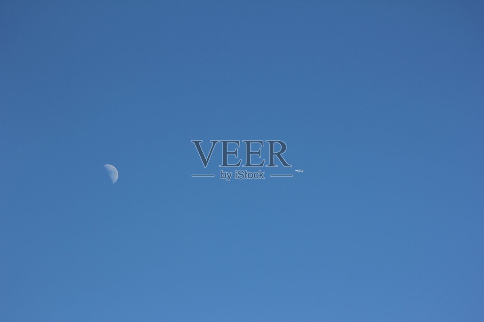 飞机在晴朗的蓝天上留下白色的凝结痕迹照片摄影图片