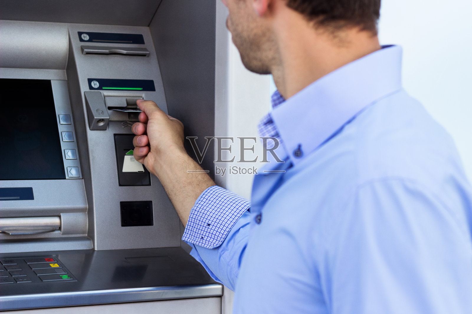 一个商人把他的信用卡放在了自动取款机上照片摄影图片