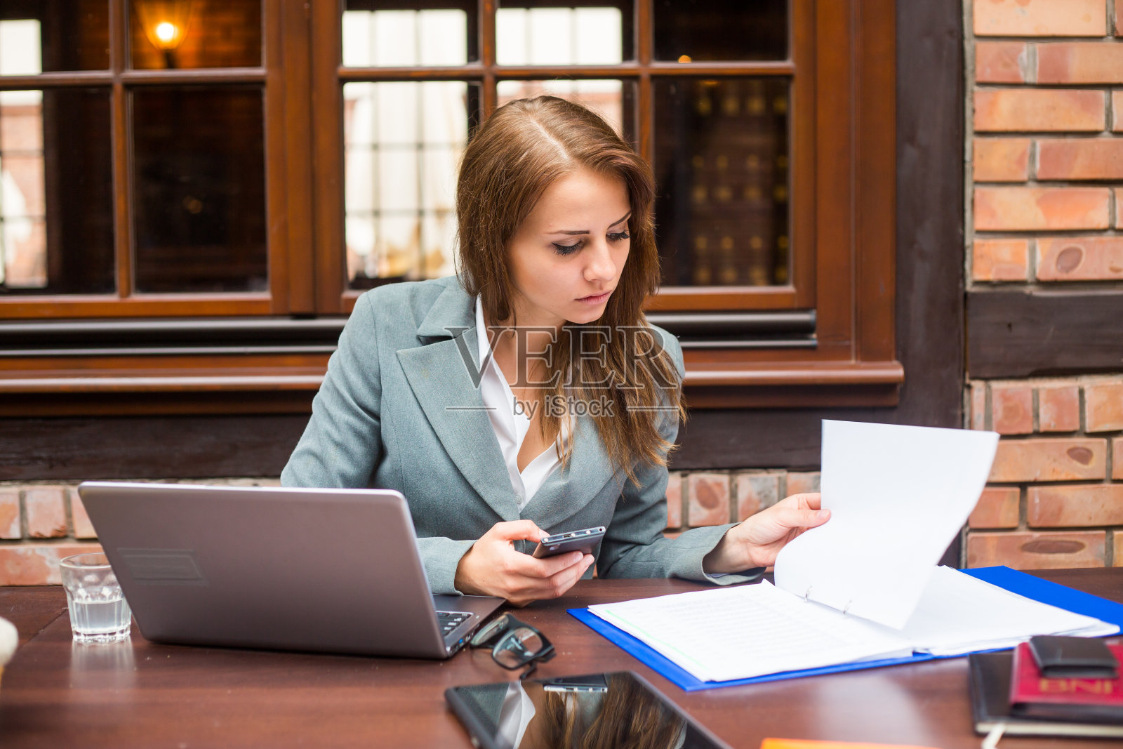 在餐厅工作的女商人，带着笔记本电脑和手机。照片摄影图片