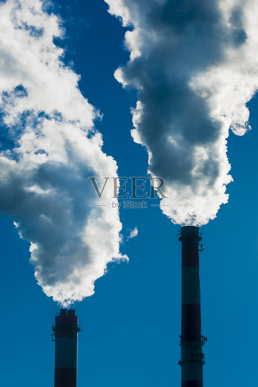 两个冒烟的烟囱。照片摄影图片