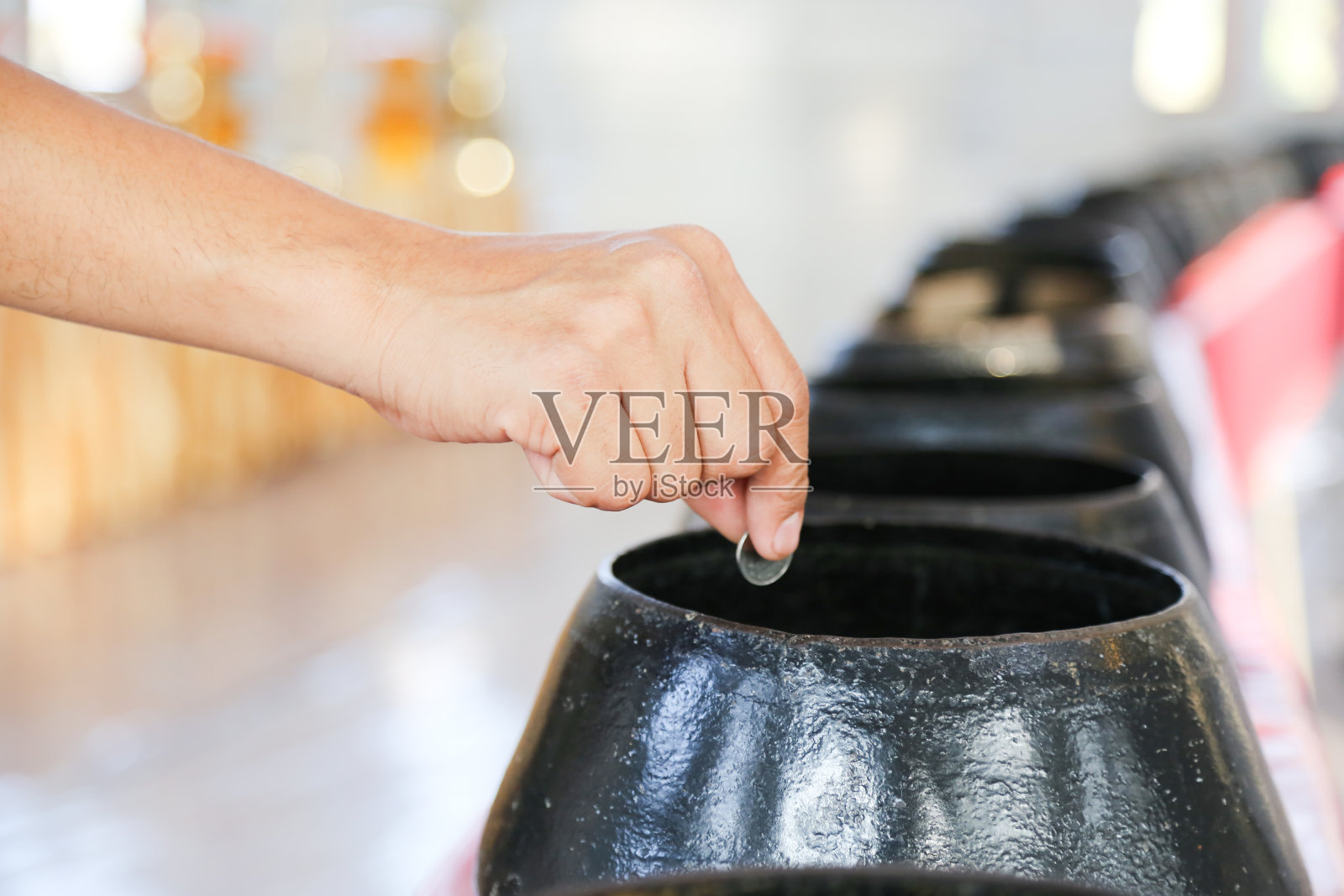 手把捐赠的硬币放入黑和尚碗照片摄影图片