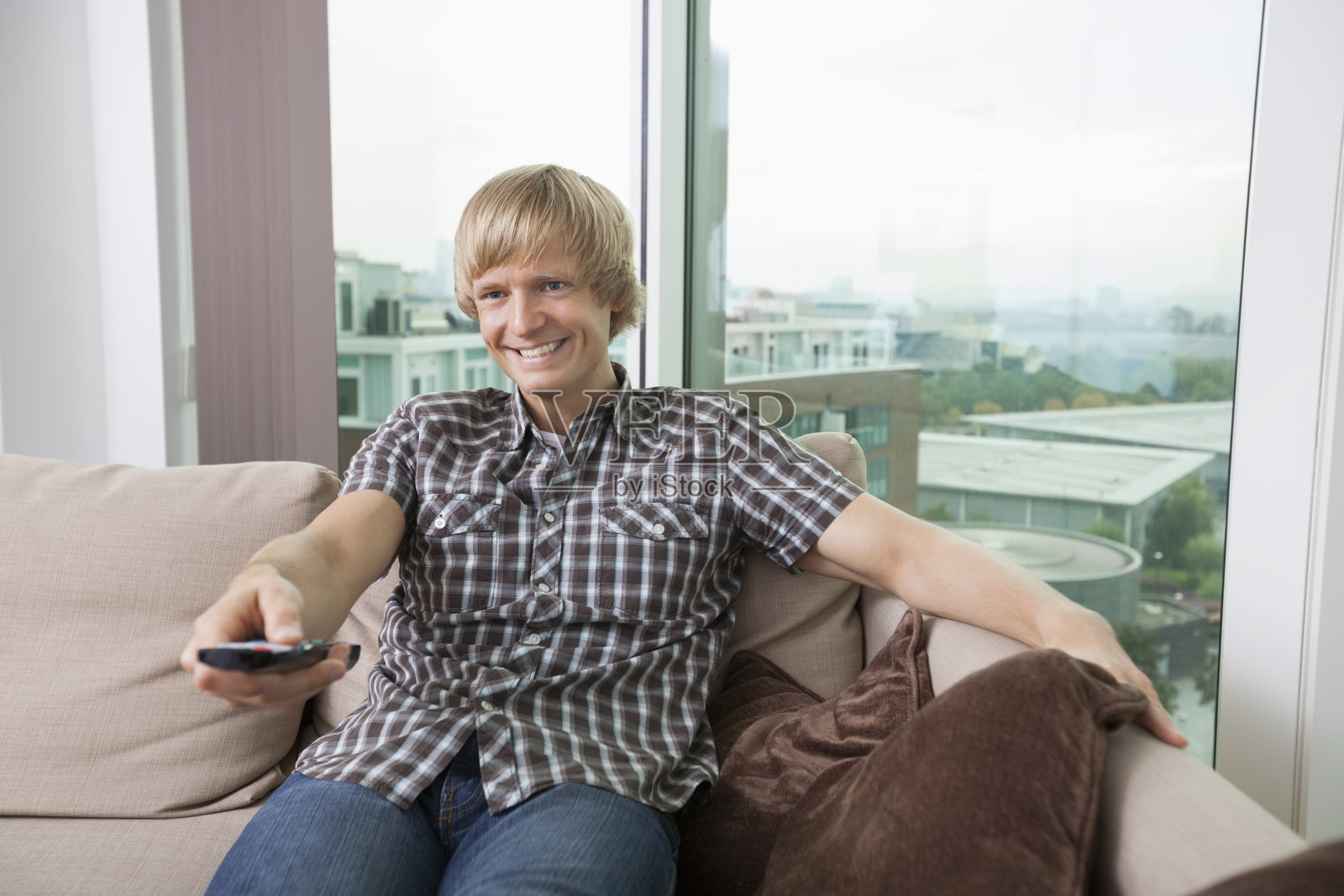 微笑着坐在沙发上看电视的中年男人照片摄影图片