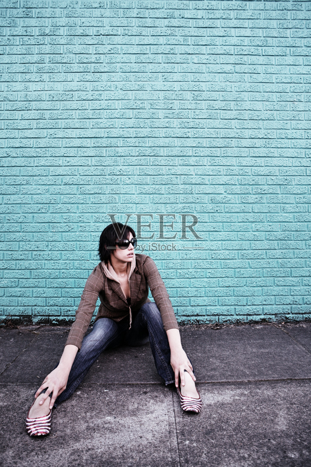 青色砖墙前的年轻女子照片摄影图片