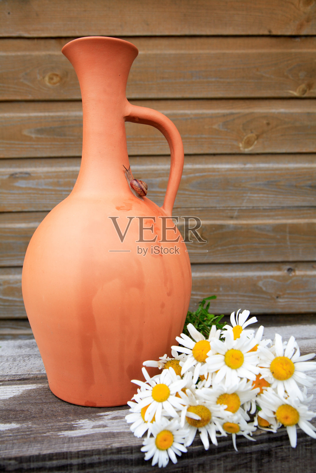 木墙边放着陶罐和一束甘菊照片摄影图片