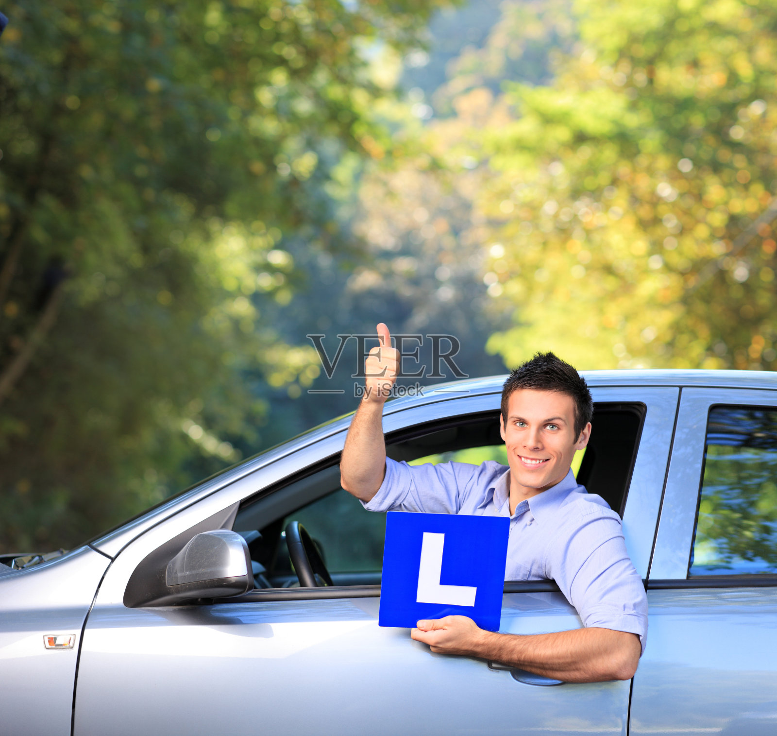 快乐的男人举着L的牌子，竖起大拇指照片摄影图片