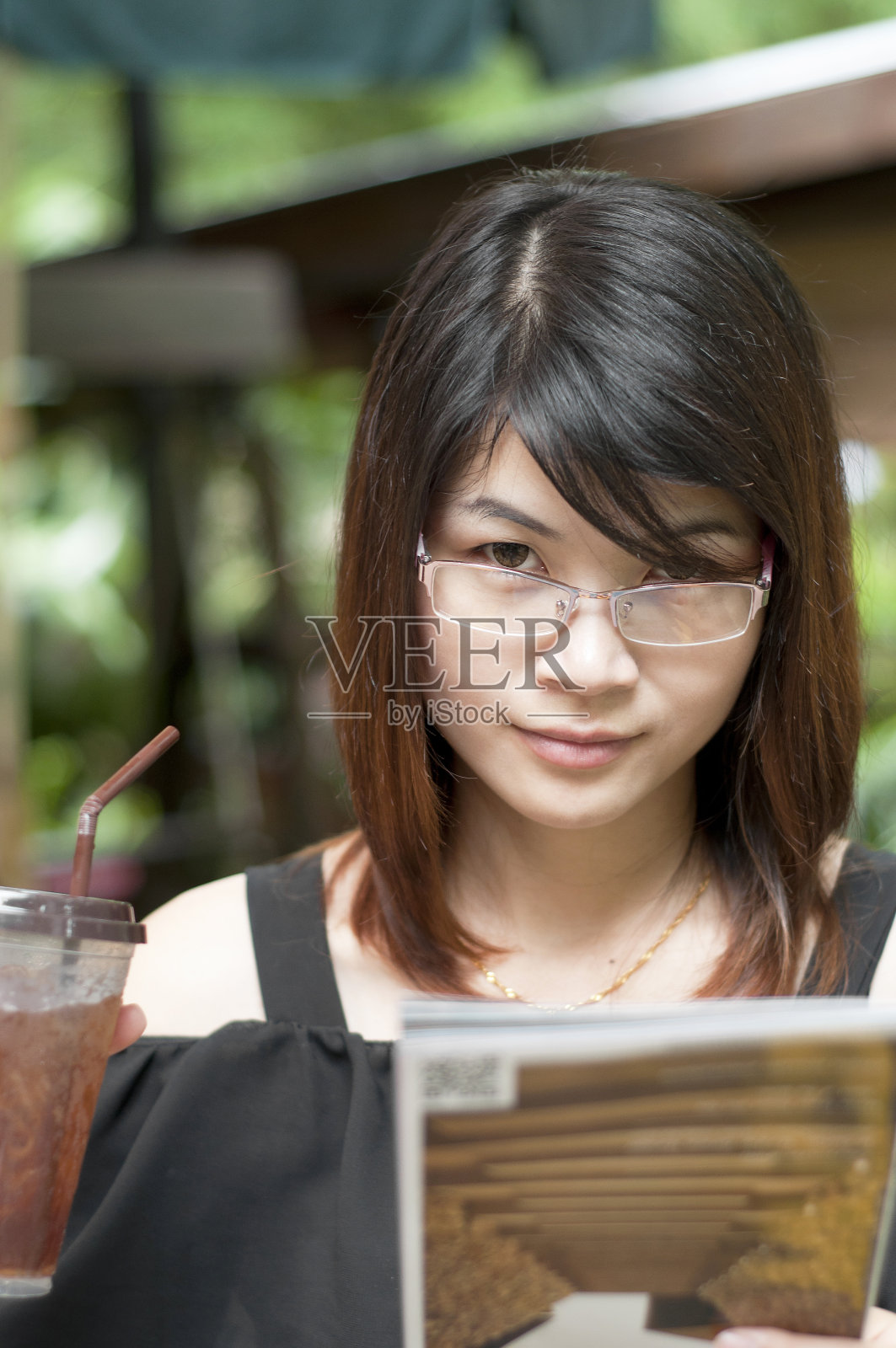 美丽的亚洲女人享受冰茶和持有旅游地图。照片摄影图片