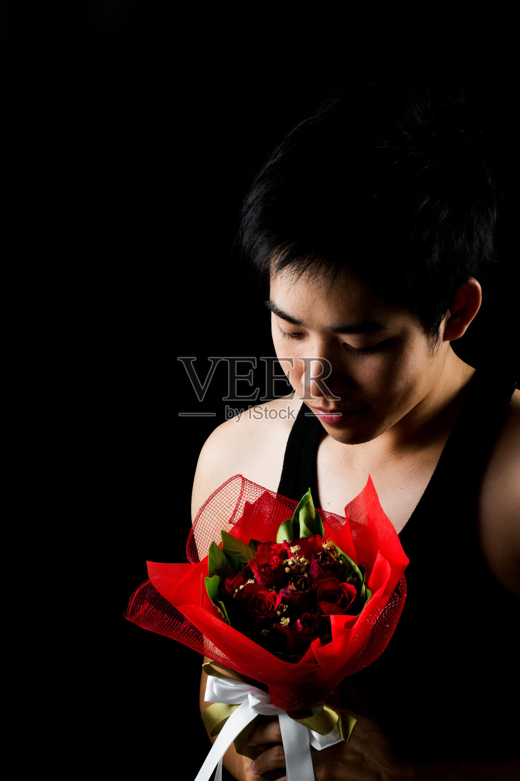 亚洲男孩与红色花束在黑暗的背景照片摄影图片