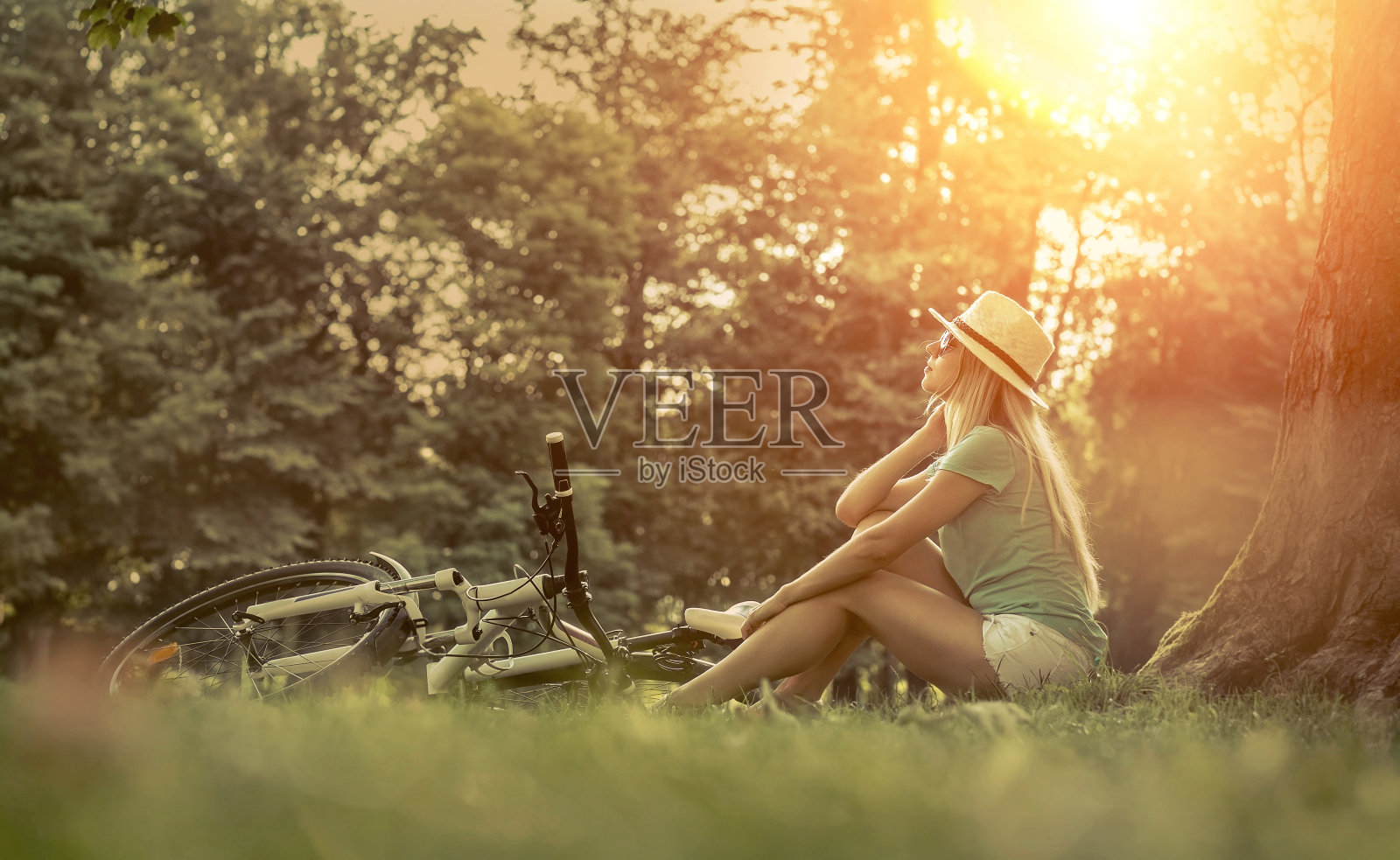 在阳光下坐在自行车旁的女人照片摄影图片