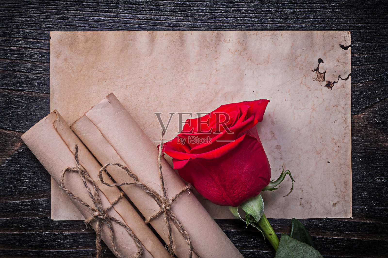 老式绳纸卷轴，红玫瑰在木板上照片摄影图片