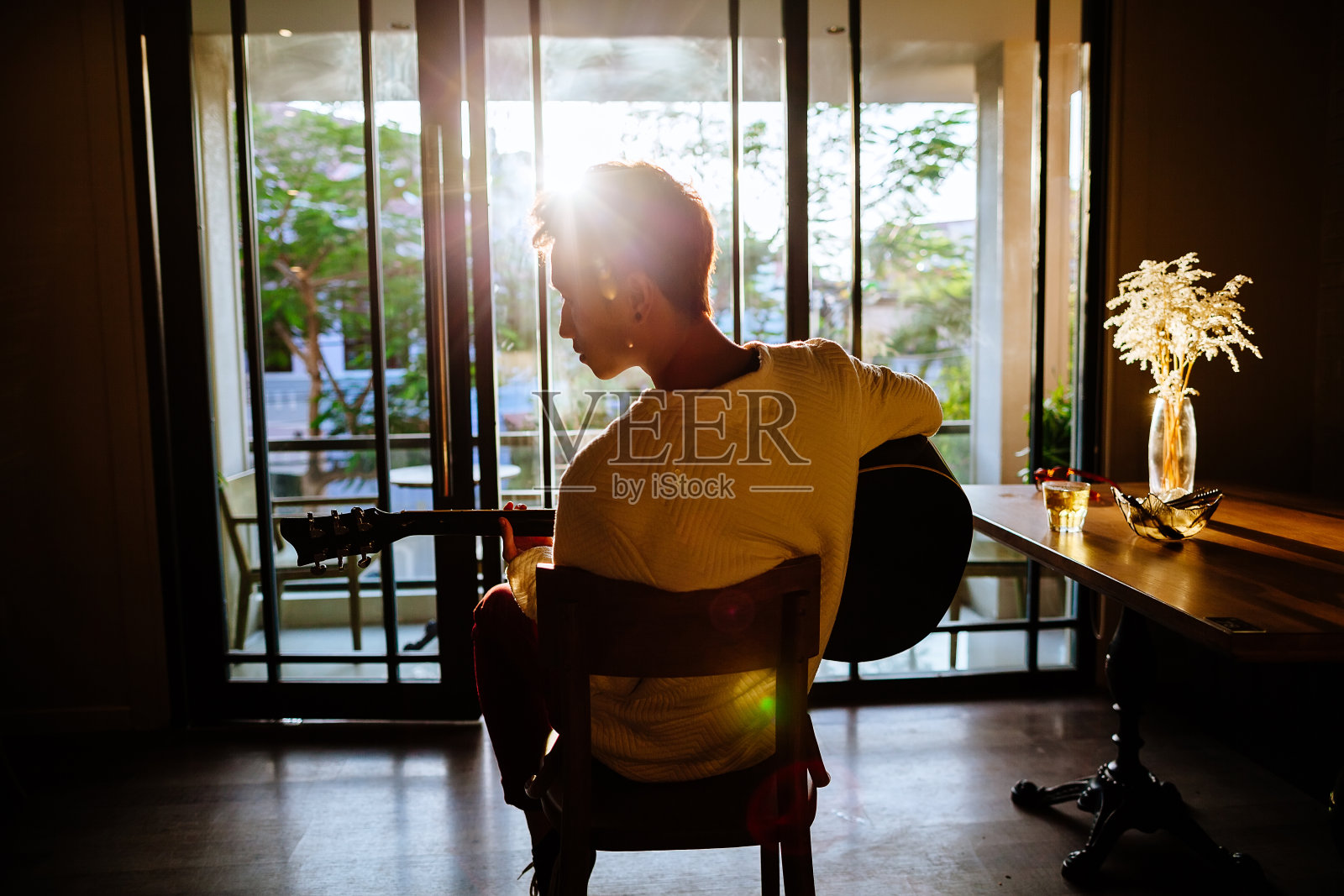 亚洲艺术家男子在咖啡馆的阳光弹吉他照片摄影图片