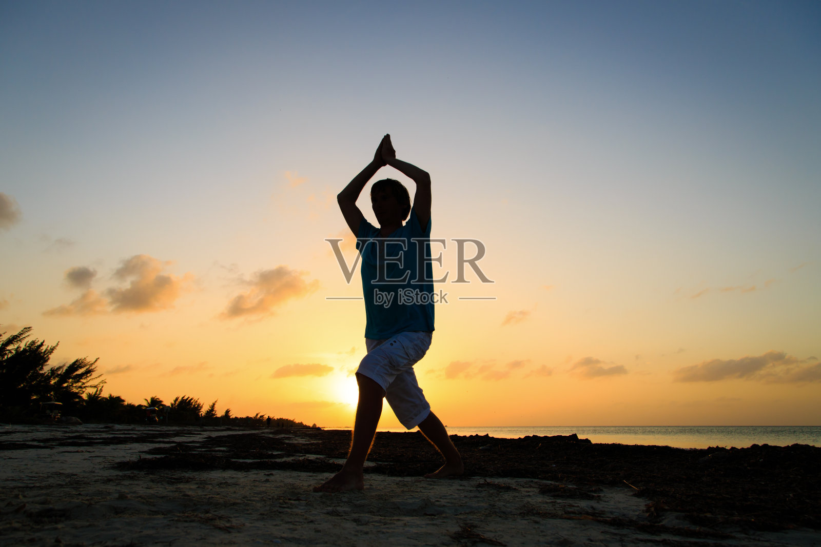 日落时做瑜伽的年轻人的剪影照片摄影图片