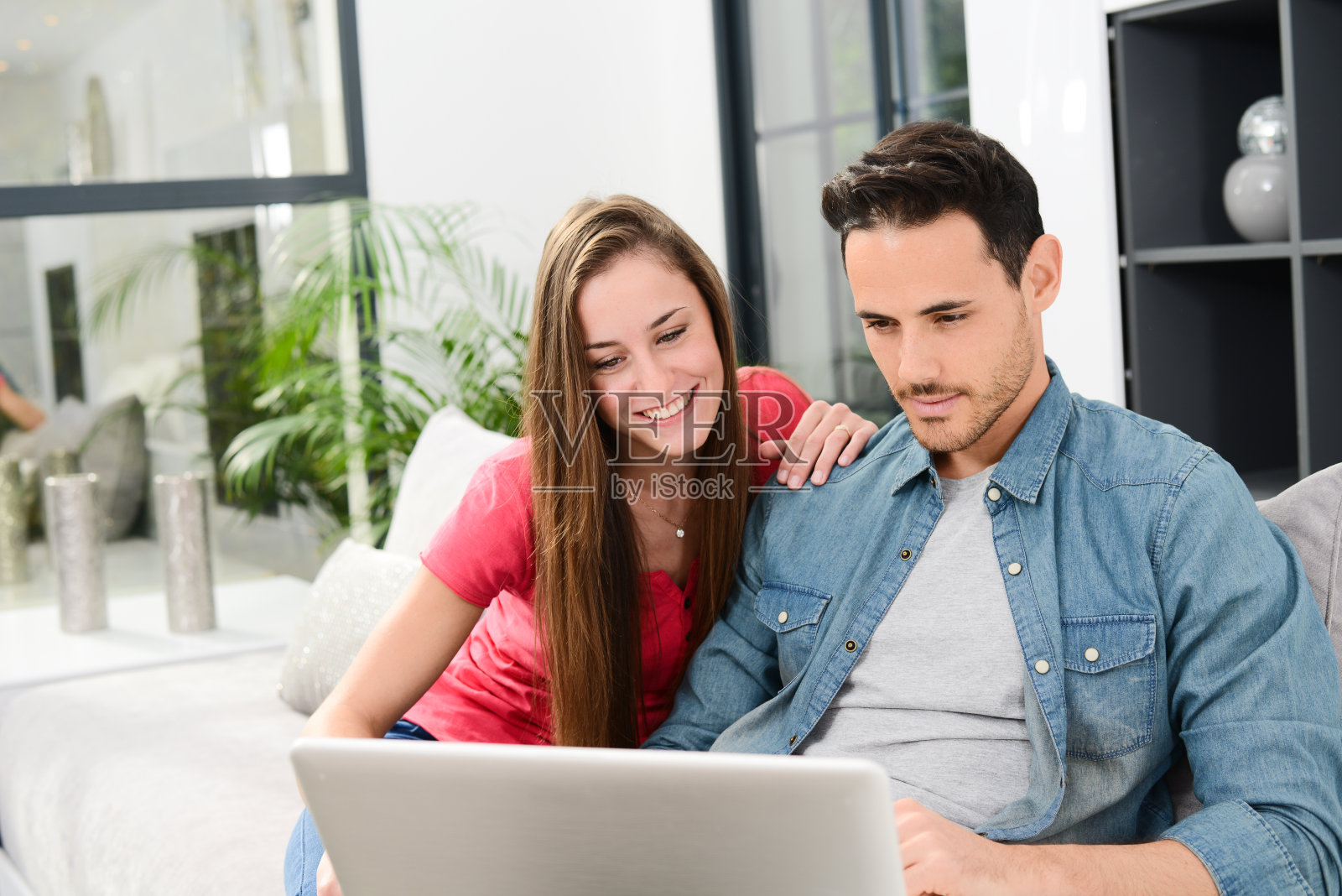 幸福的年轻夫妇在家里的沙发上用笔记本电脑照片摄影图片