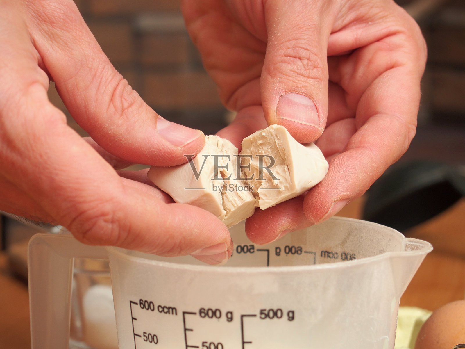 将新鲜酵母加入量杯。照片摄影图片