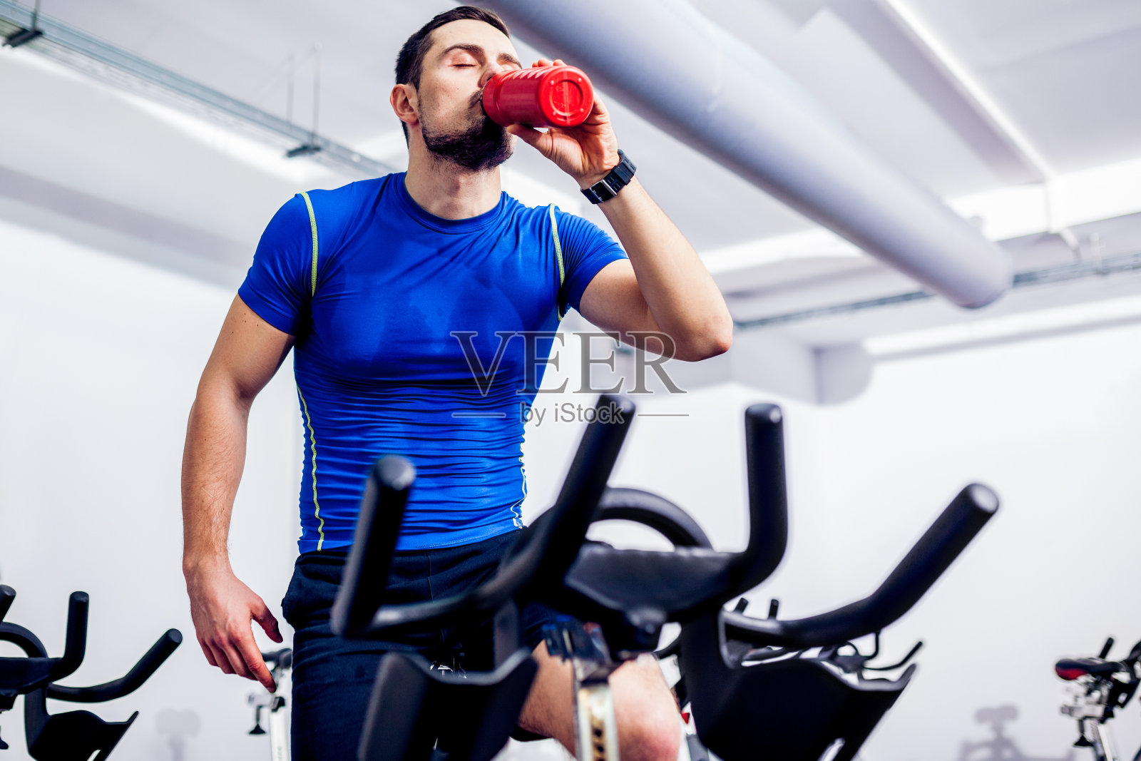 一个健身教练从一个红色的瓶子里喝了一口水照片摄影图片