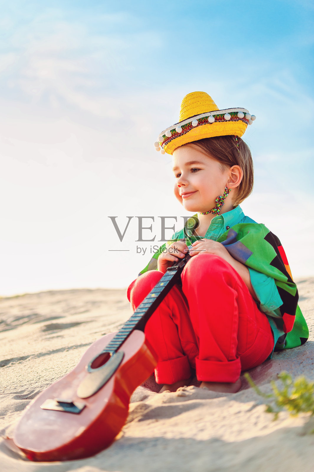 笑容可掬的小男孩在弹吉他照片摄影图片