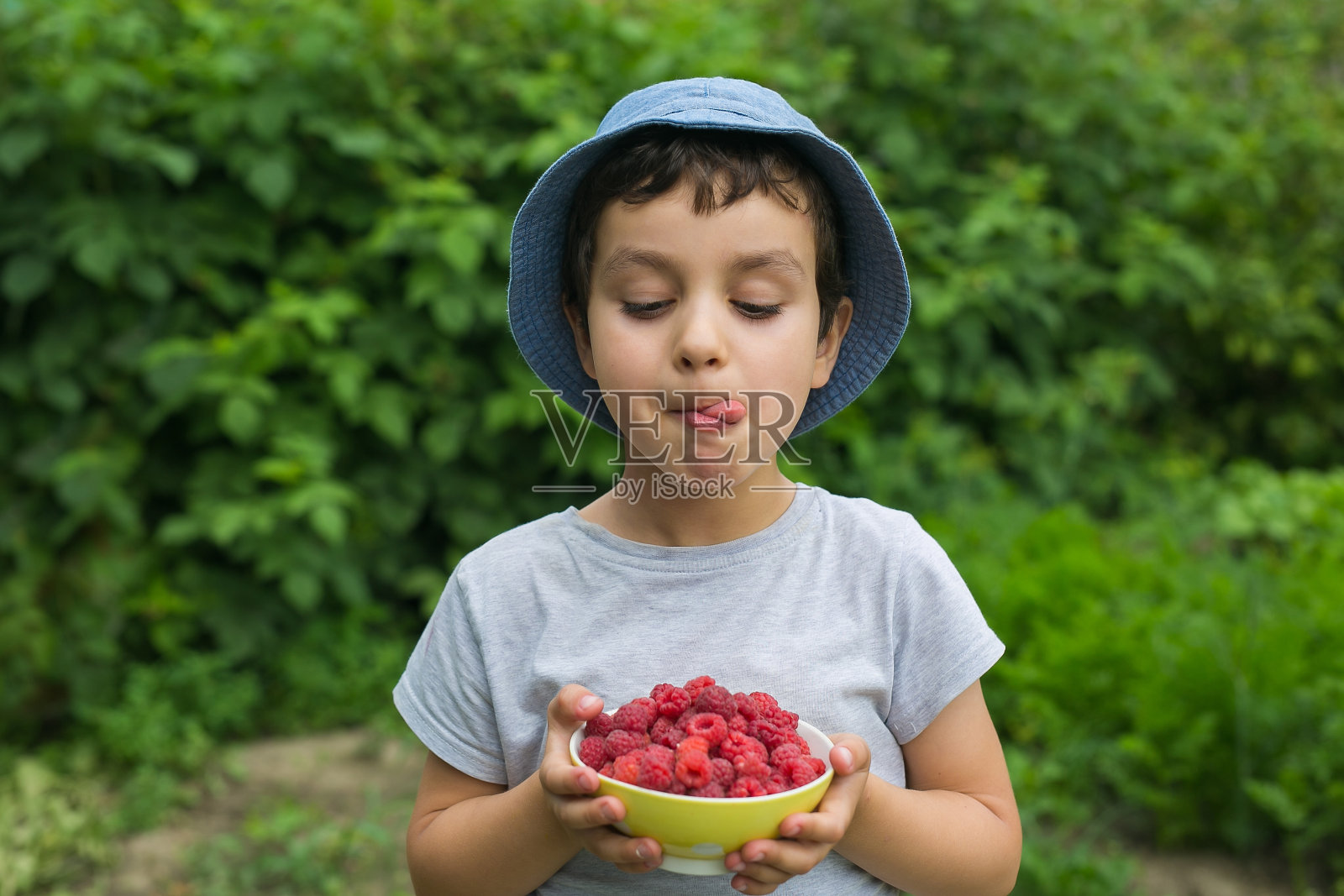可爱的小男孩看着盘子，舔了舔自己照片摄影图片