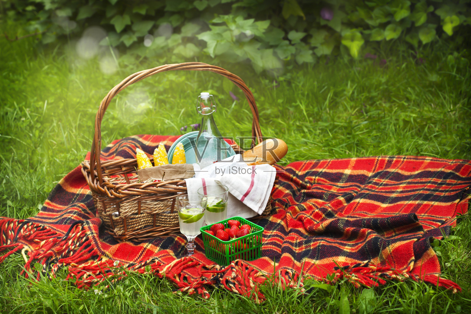 野餐篮子，有浆果，柠檬水，玉米和面包。照片摄影图片