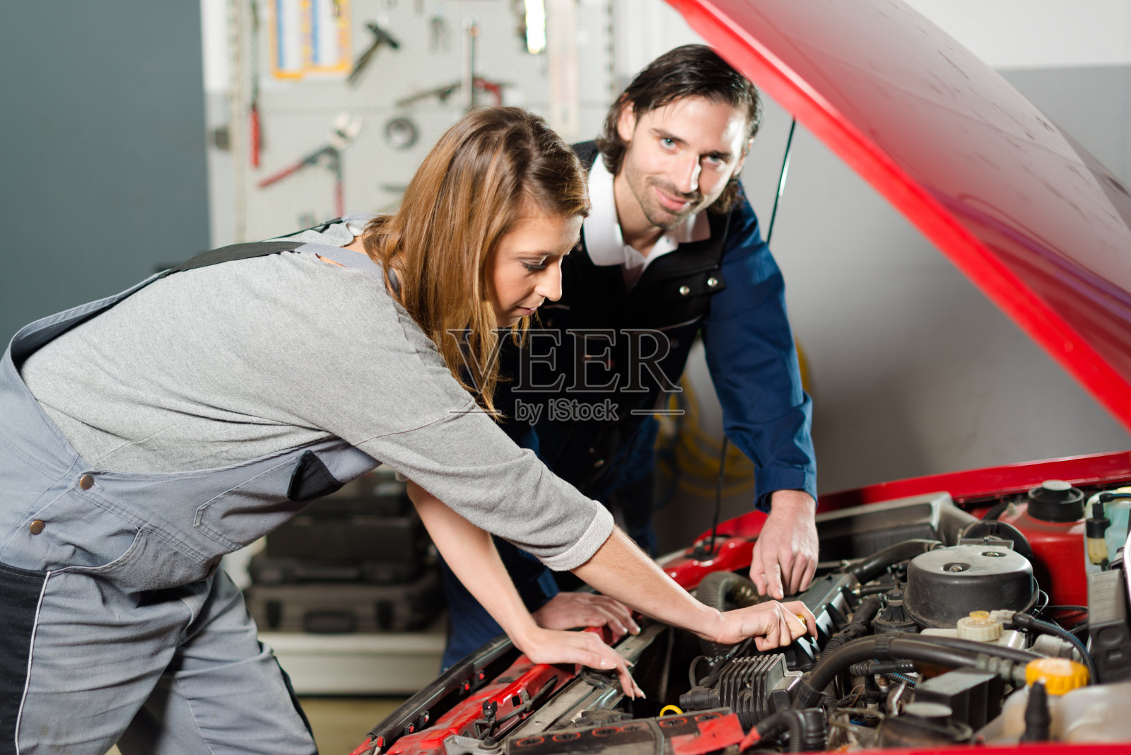 汽车修理工在车库里指导一名女学员照片摄影图片