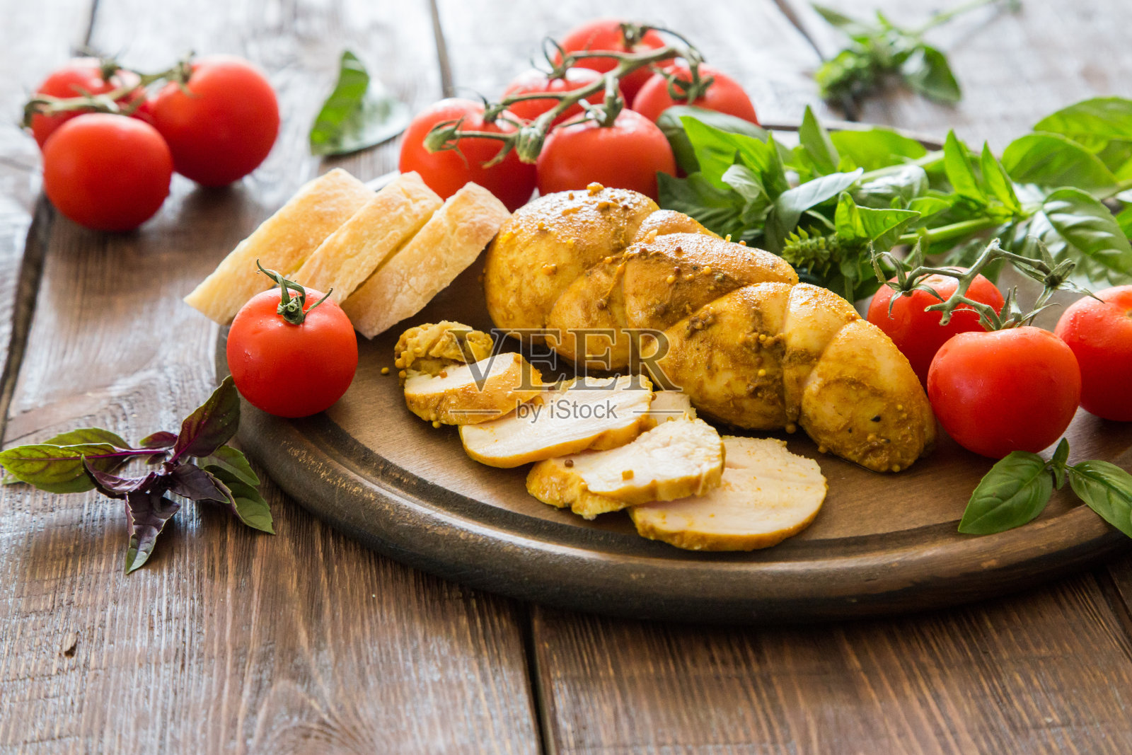 烤鸡胸肉(熏牛肉)配香料，番茄和罗勒。照片摄影图片