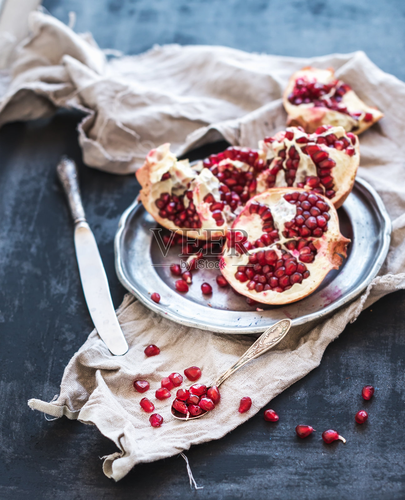 红熟去皮的石榴放在质朴的金属板上照片摄影图片