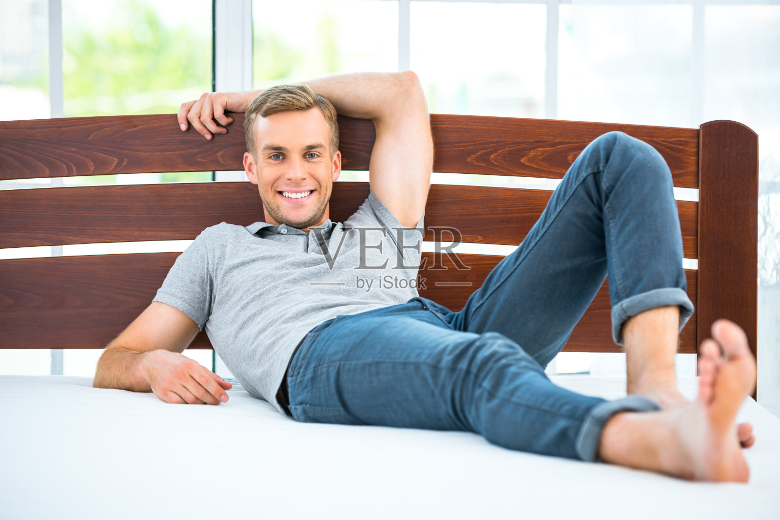 年轻人躺在白色的床上照片摄影图片