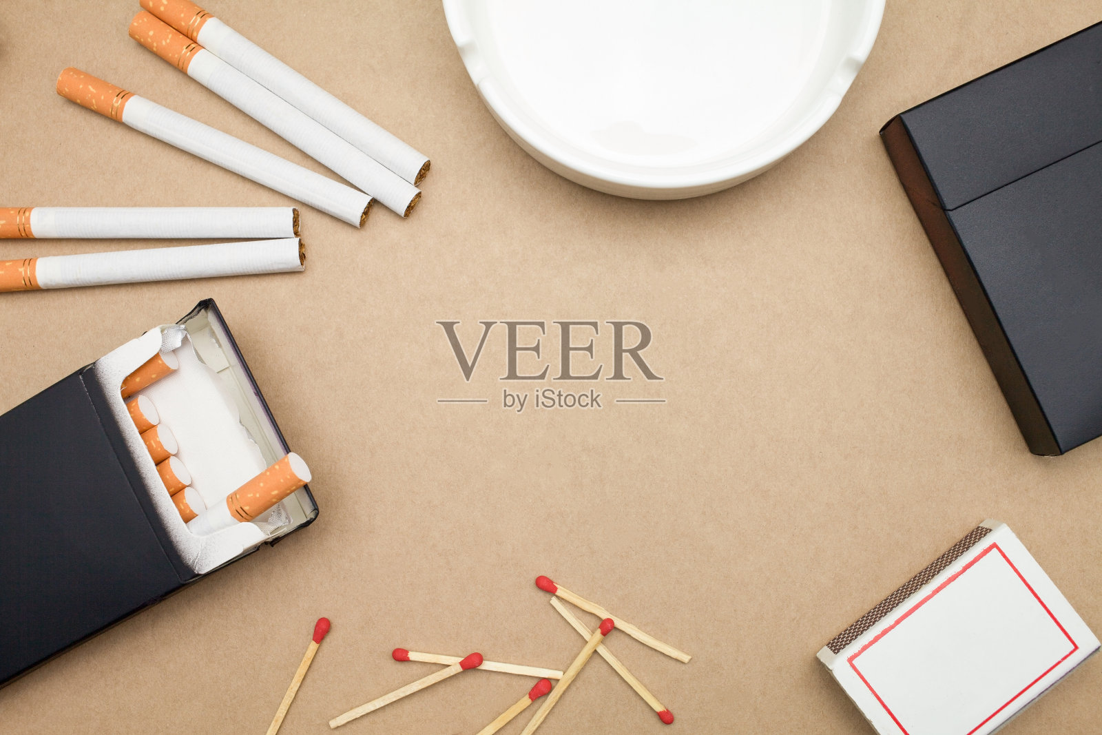 棕色背景上的香烟、烟盒、火柴和烟灰缸照片摄影图片