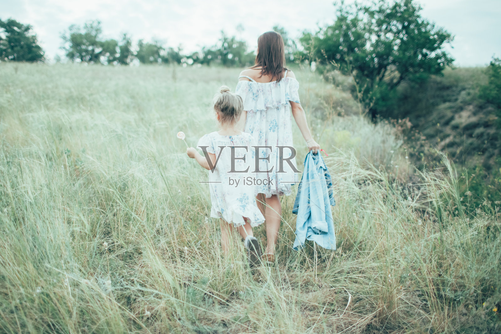 年轻的母女站在绿草的背景上照片摄影图片