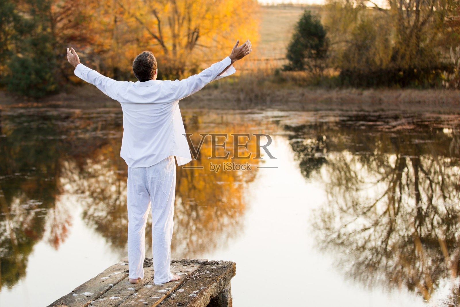 年轻人站在码头上，双臂张开照片摄影图片