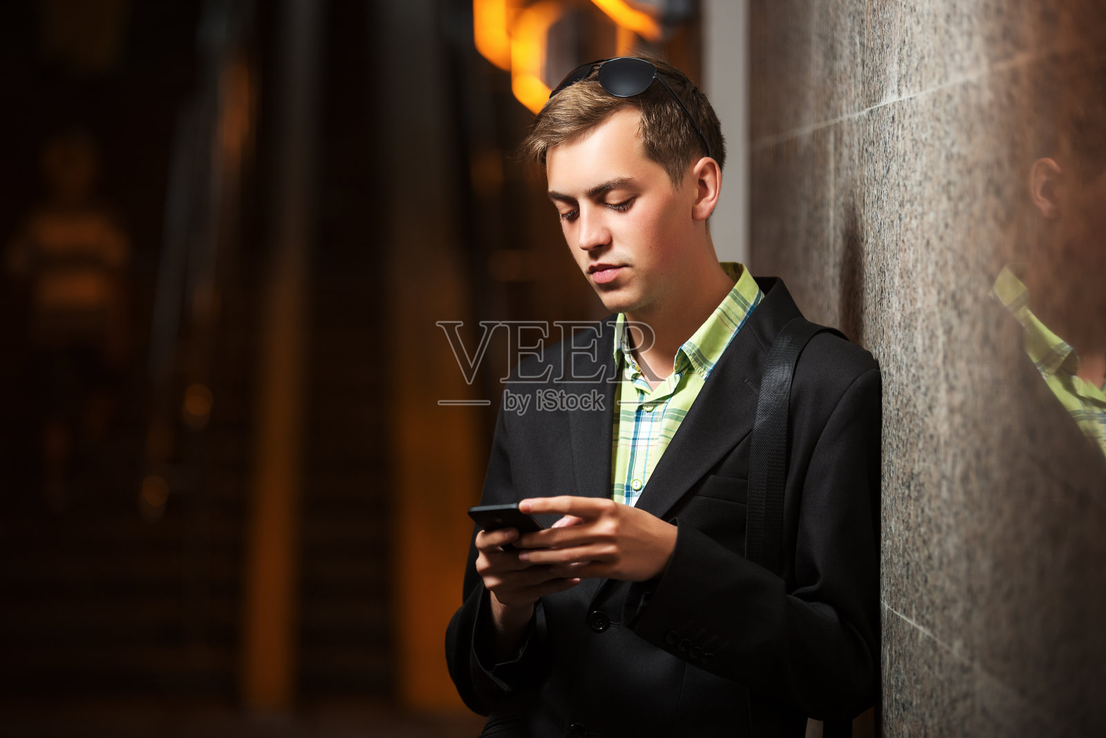 一个年轻人拿着手机站在墙上照片摄影图片