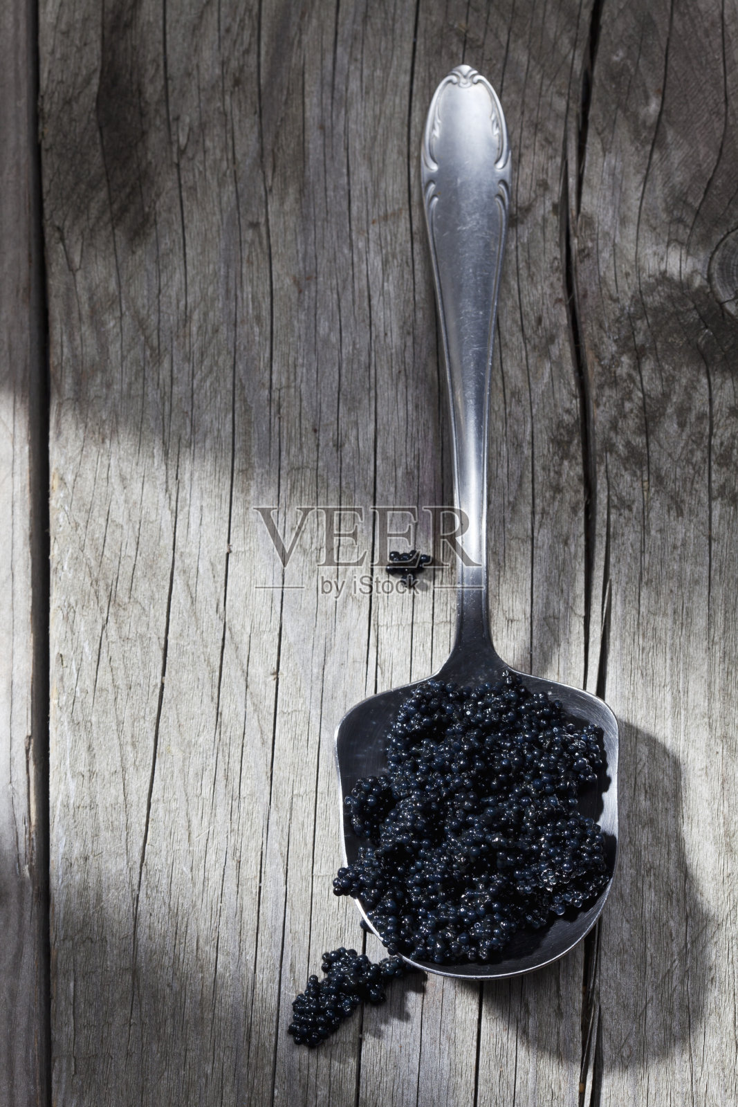 木头上的旧勺子上的黑鱼子酱照片摄影图片