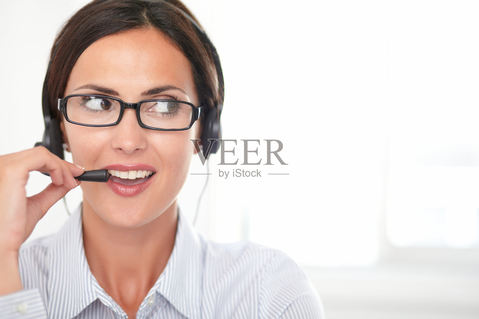 自信的年轻秘书戴着耳机说话照片摄影图片