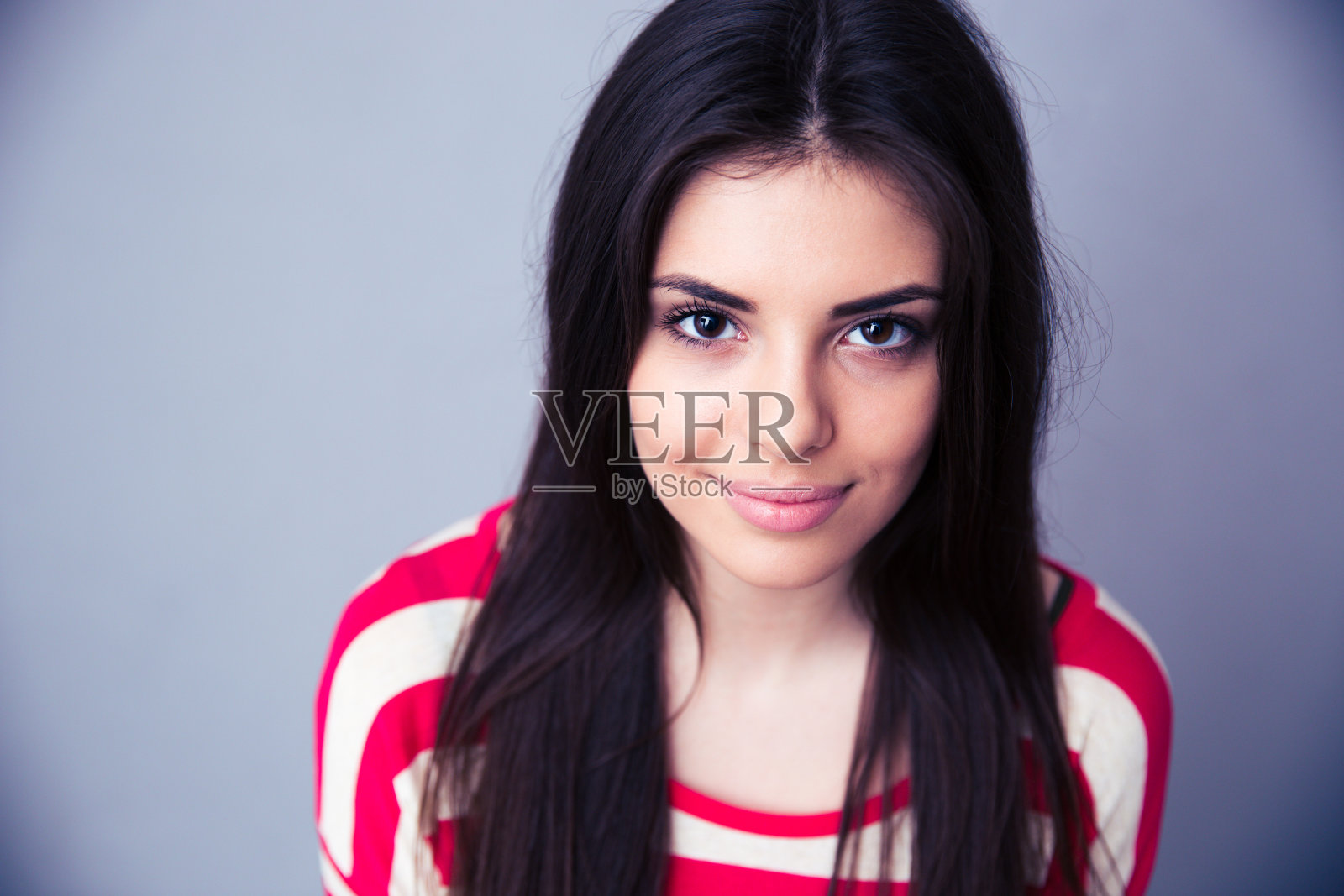 一个漂亮的年轻女人的肖像在灰色的背景照片摄影图片