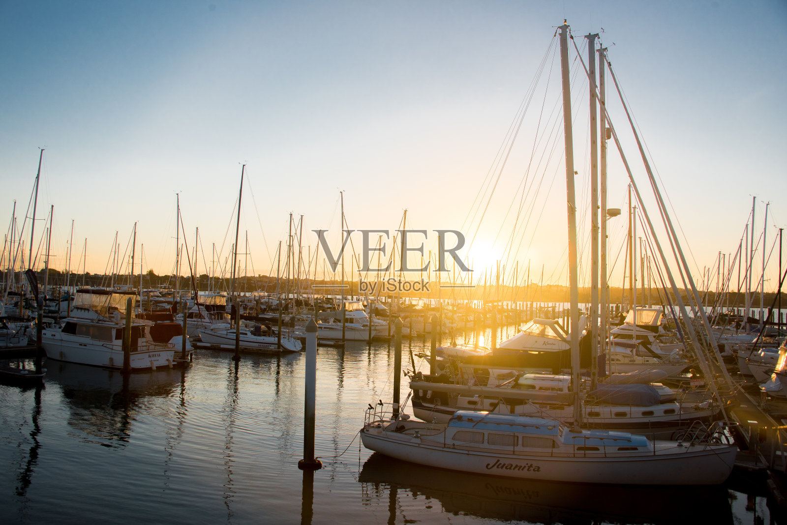 日落时，小船和游艇停泊在码头上照片摄影图片