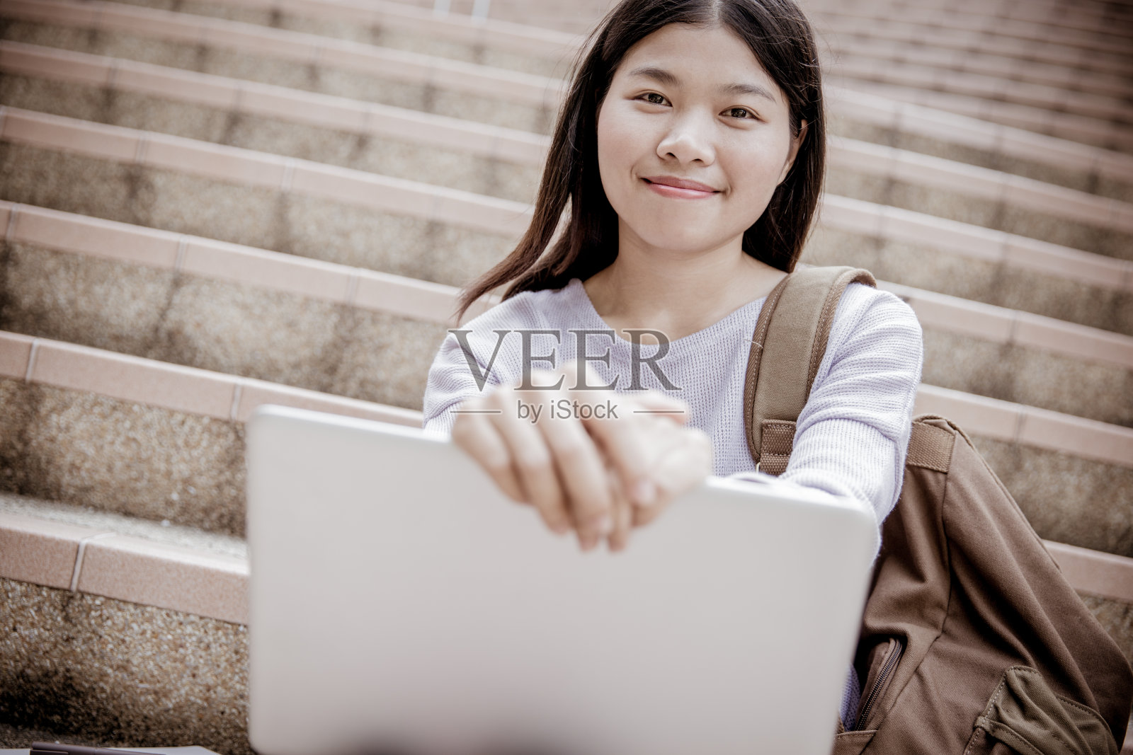 年轻女子在户外的台阶上使用笔记本电脑照片摄影图片