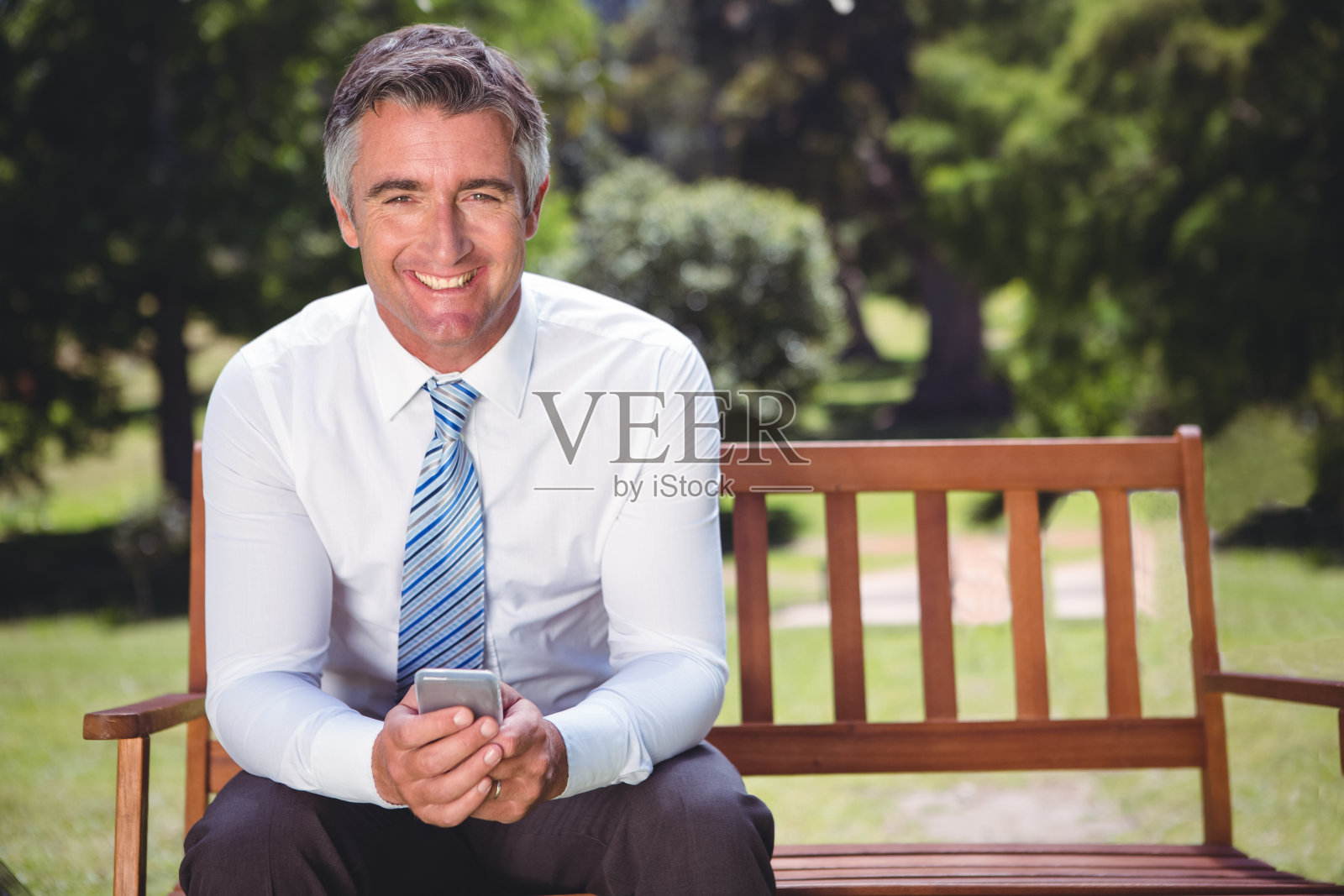 一个商人在公园里用手机照片摄影图片