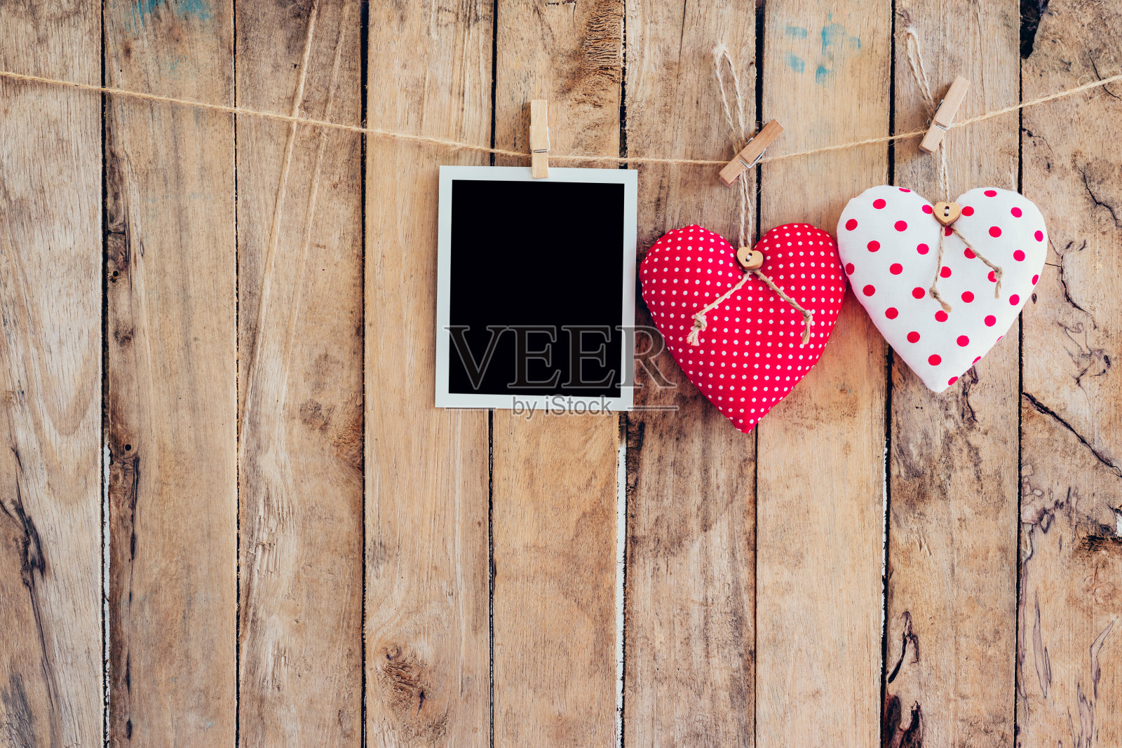 两个心形和相框挂在晾衣绳上，木制背景。照片摄影图片