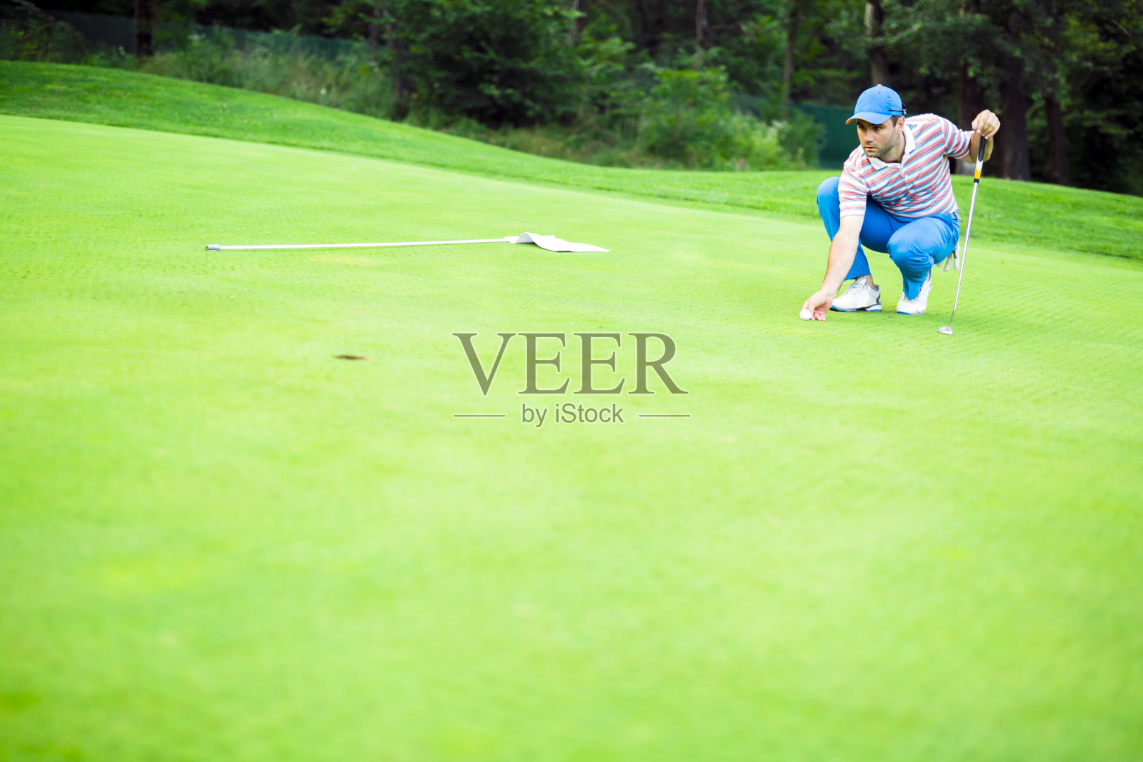 在果岭上标记球的高尔夫球手照片摄影图片