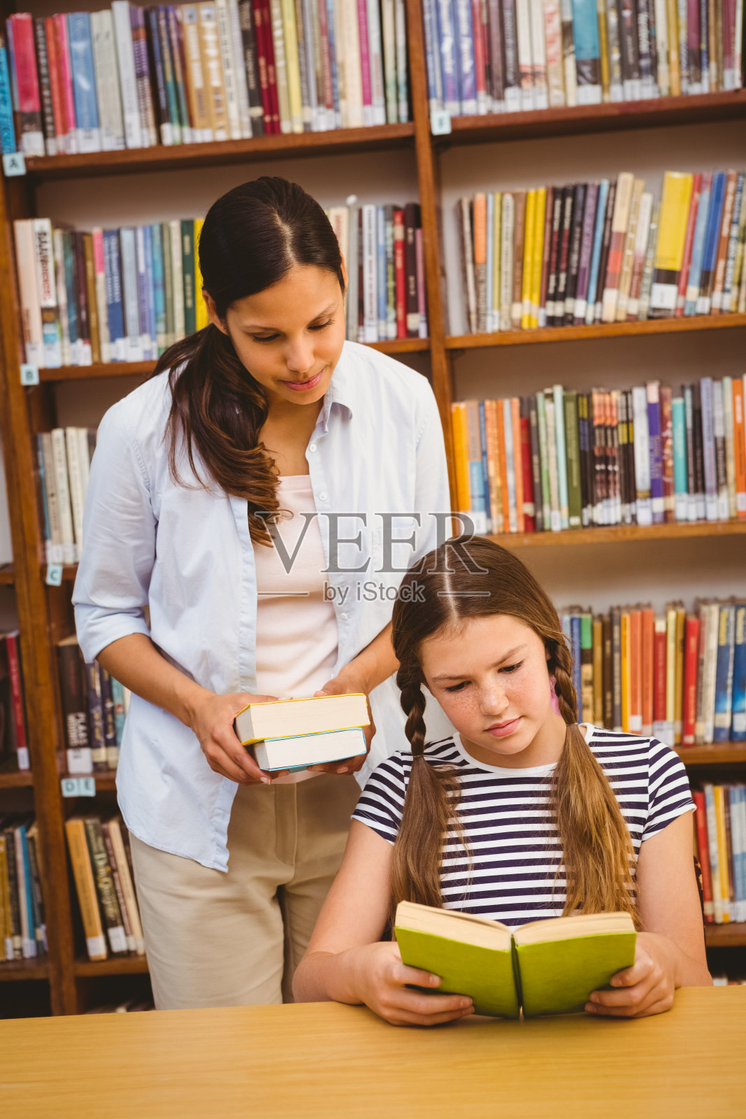 老师和女孩在图书馆看书照片摄影图片