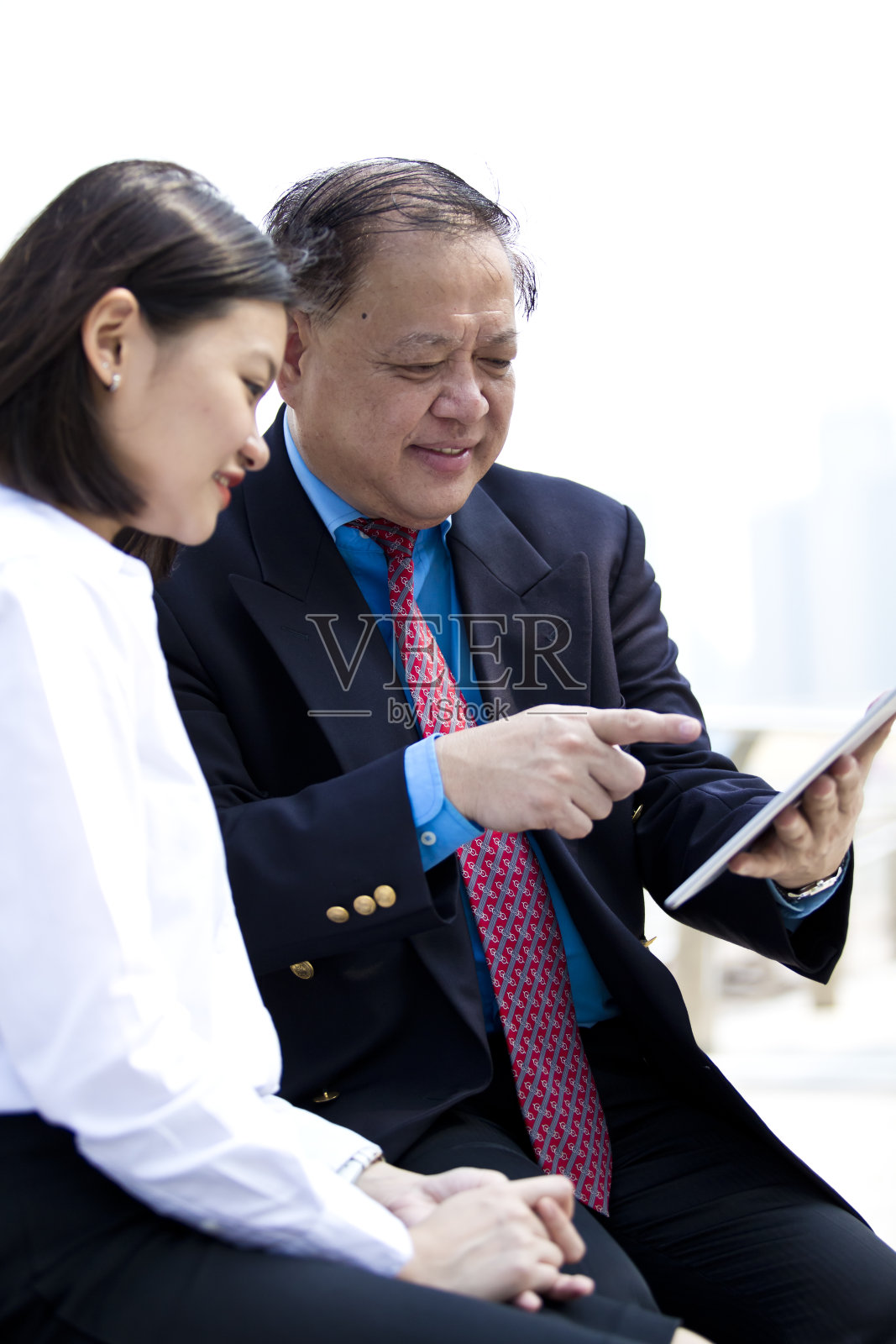 使用平板电脑的亚洲商人和年轻女性高管照片摄影图片
