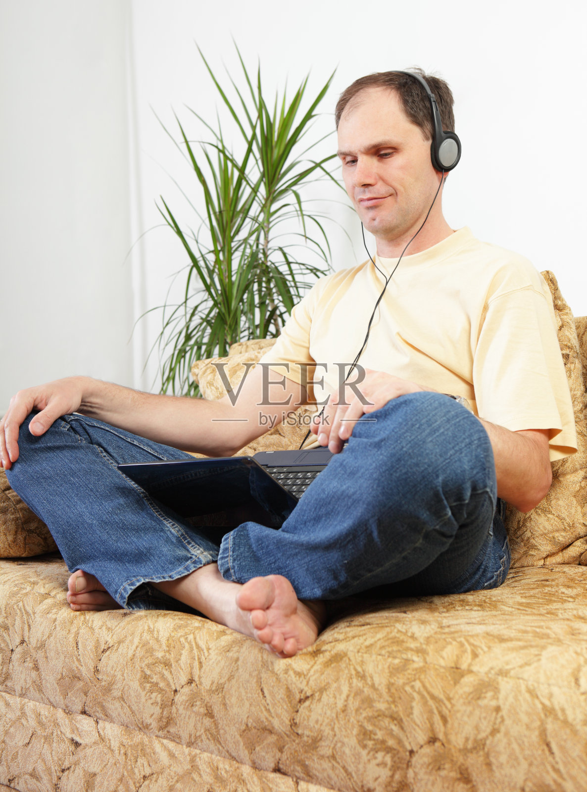 沙发上拿着笔记本电脑的男人”照片摄影图片