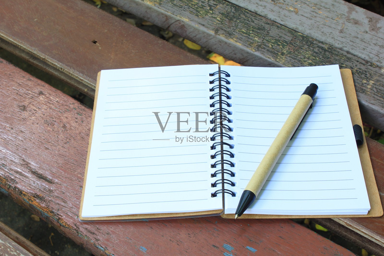 笔记本和笔放在棕色的长凳上照片摄影图片